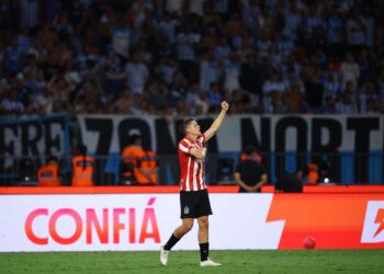 Jogador do Estudiantes comemora em campo diante da torcida no Alt, título e descrição.